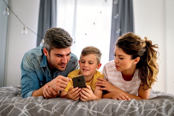 Happy technology addicted family parents and kid use laptop phone digital tablet at home