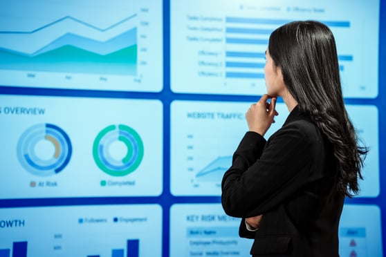 Businesswoman analyzing reports before digital dashboards