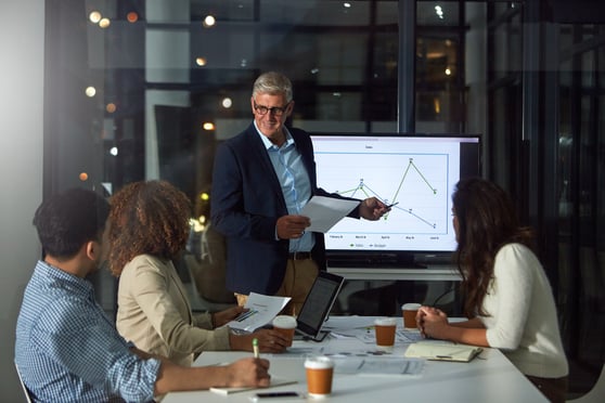 Man, presentation and team in office at night with finance report, data analysis and profit