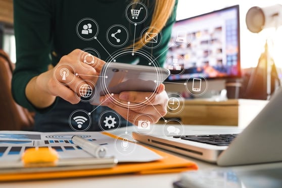 Person using a smartphone with icons representing connected digital marketing channels such as social media, eCommerce, email, and analytics.