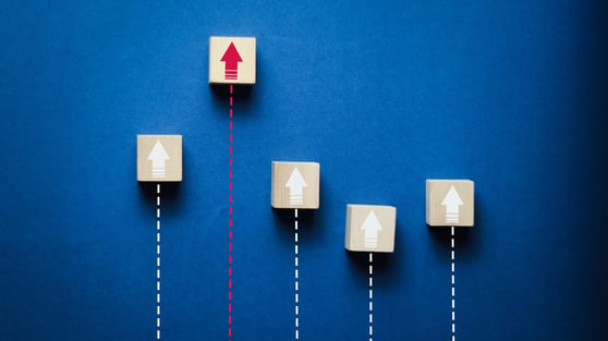 Wooden blocks with upward arrows on a blue background symbolize business growth, leadership, success, performance improvement