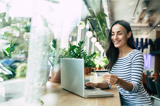 Woman using laptop and doing shopping online with her smartphone and card