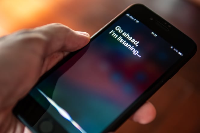 Person holding a smartphone while a voice assistant listens for a spoken search query.