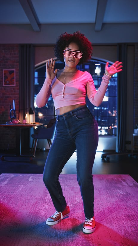 Woman dancing in neon lights while filming a short-form social media video.