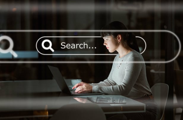 A woman using a laptop with a digital search bar overlay, representing the impact of AI on SEO.