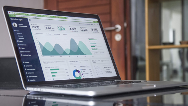 Laptop open on a desk, with analytics reports on the screen.