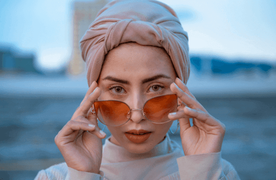 Woman is lowering her stylish sunglasses and starting back at you.