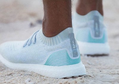 Adidas and Parley blue and white running shoes on sand