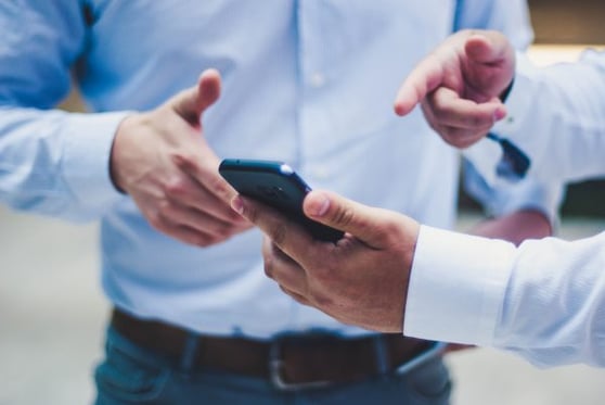 Two people standing over a cell phone.