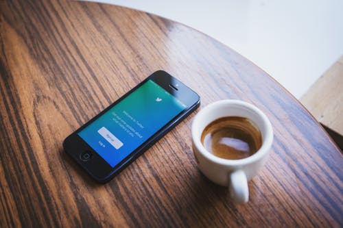 Photo of cell phone and coffee cup on a table.