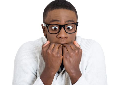 Photo of a man looking scared, with his hands covering his mouth.