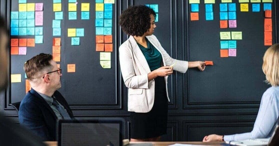 Lady standing in front of a board filled with sticky notes.