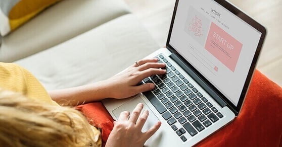 Woman sitting with an open laptop on her lap.