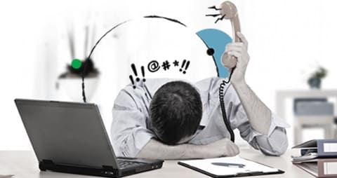 Graphic of a frustrated man holding a phone, with his head on his desk with an open laptop.