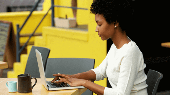 Woman sitting at a desk, typing on a laptop.