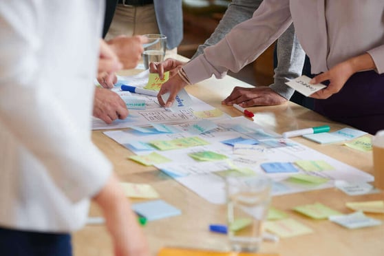 Team collaborating on a branding strategy with sticky notes and papers, discussing brand awareness services.