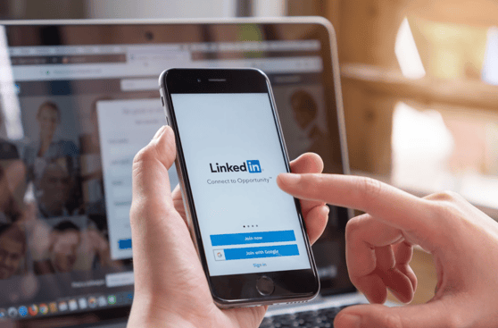 Hands holding a mobile device with the LinkedIn login page.