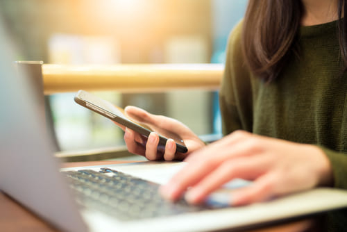 Woman connecting cellphone and laptop computer-1