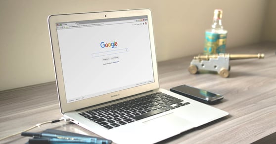 Open laptop on a desk, with the Google Search engine ready on the screen.
