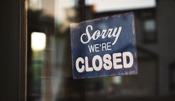 Sign hanging on a business door, it says 'Sorry We're Closed'.