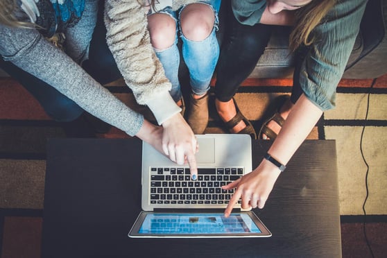 Three people working on a single laptop