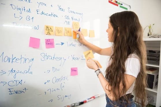 Woman in front of a whiteboard, brainstorming with sticky notes.
