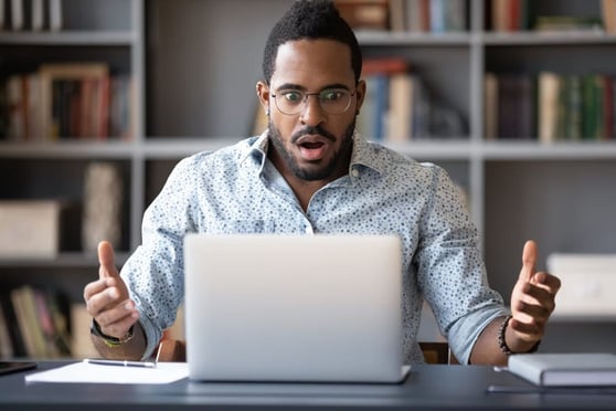 Front view shocked millennial african american man in glasses looking at laptop screen