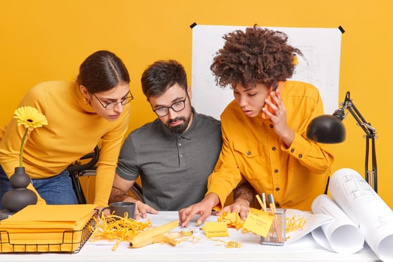 Group of coworkers try to find mistake in yellow background.