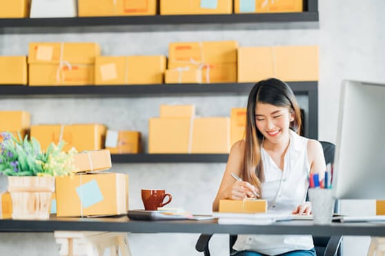 Smiling woman sitting at her desk, taking notes